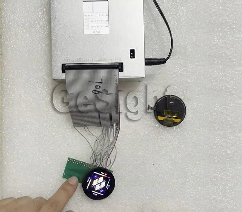 Demo kit setup showing a round AMOLED display connected to a controller board and ribbon cable.